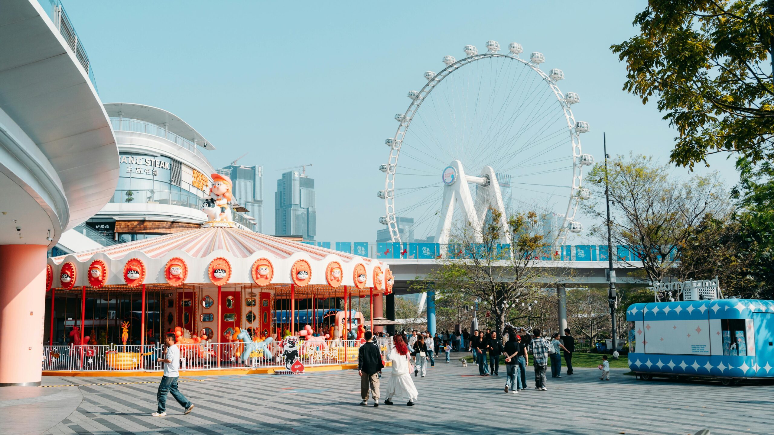 A lively urban park featuring a ferris wheel, carousel, and visitors enjoying a sunny day.